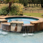 round stone work spa with dual overflow channels into pool