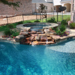 round spa with river rock waterfall into pool
