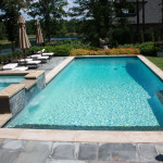 better view of rectangular pool with square spa and seating area with chaise lounge chairs with white cushions