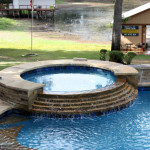 round spa with stepped waterfall into pool
