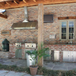 outdoor kitchen with vent hood and stainless steel appliances against chicago style brick
