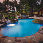 curved edge pool with flat water spouts, lighting and stone work