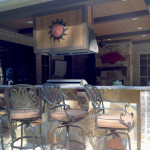outdoor kitchen with sun clock and wrought iron bar stools